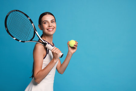 Happy tennis player with racket and ball on light blue background, space for textの写真素材