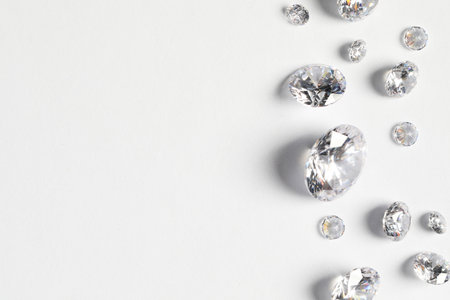 Many beautiful shiny diamonds on white background, flat lay. Space for textの写真素材