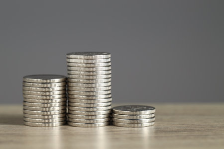 Stacked coins on wooden table against gray background, closeup with space for text. Salary conceptの写真素材