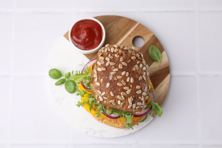 Delicious vegan burger with chickpea cutlet on white tiled table, top viewの写真素材