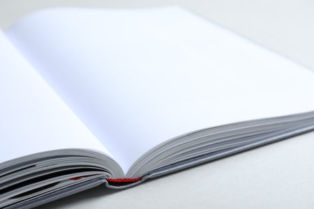 Open book with hard cover on light gray table, closeup