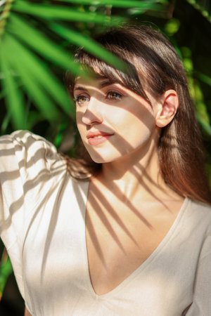 Portrait of beautiful woman in shadow of tropical leaf outdoorsの写真素材