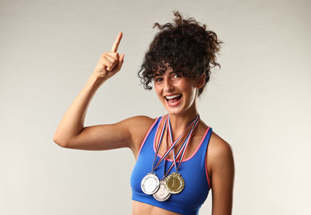 Happy winner with different medals pointing upwards on light gray backgroundの写真素材