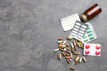 Pharmacist. Different pills and plastic bottle on gray table, flat lay. Space for textの写真素材