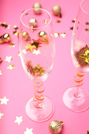 Wine glasses with confetti on pink background, closeup. Christmas decorの写真素材