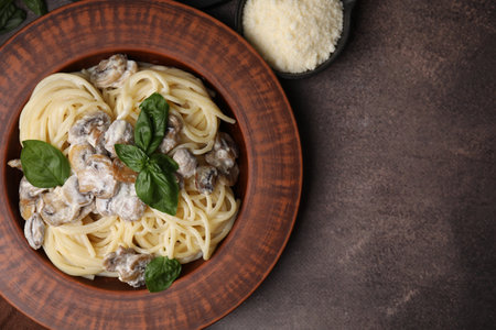 Delicious pasta with mushrooms and basil on brown table, flat lay. Space for textの写真素材