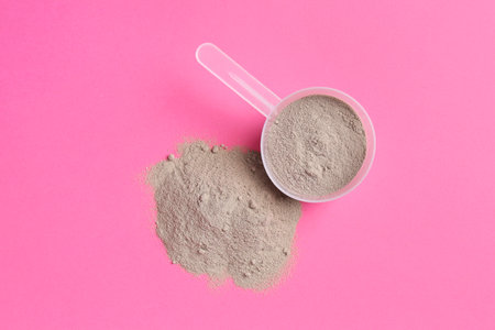 Protein powder and scoop on pink background, top viewの写真素材