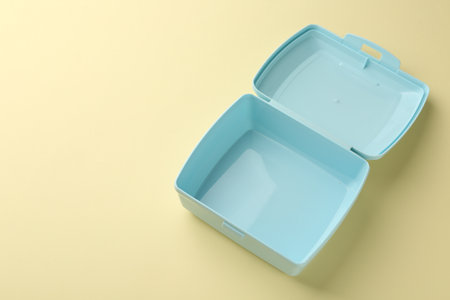 One empty lunch box on beige background, above view. Space for text