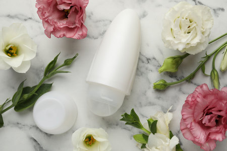 Roll-on deodorant and beautiful eustoma flowers on white marble table, flat layの写真素材