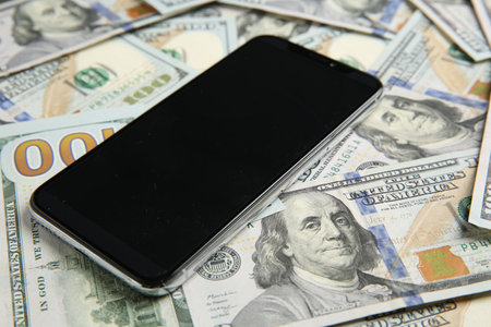 Modern smartphone on dollar bills, closeup view