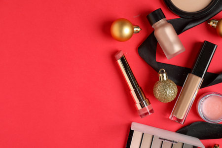 Flat lay composition with makeup products and Christmas decor on red background, space for textの写真素材