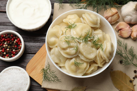 Delicious pelmeni with dill served on wooden table, flat layの写真素材
