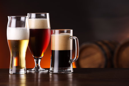 Glasses with different types of beer on wooden table in bar. Space for textの写真素材