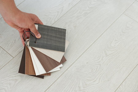 Man with samples of wooden flooring indoors, closeup. Space for textの写真素材