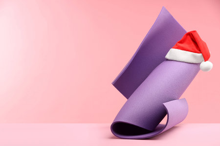 Yoga mat and Santa hat on pink background, space for textの写真素材