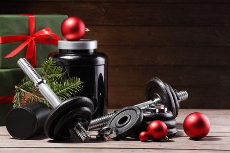 Dumbbells, container with supplement and Christmas decor on wooden tableの写真素材