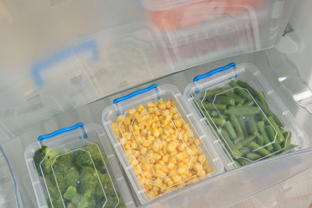 Plastic containers with different frozen vegetables in refrigeratorの写真素材