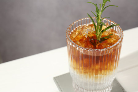 Refreshing espresso tonic drink with rosemary on white table, closeup. Space for textの写真素材