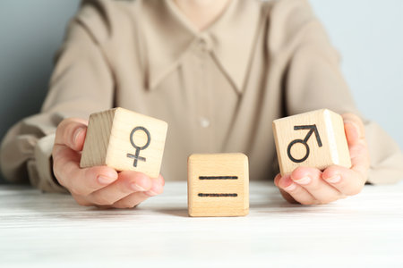 Gender equality concept. Woman with wooden cubes of male and female symbols at white table, closeupの写真素材