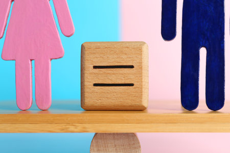 Gender equality concept. Cube with equals sign between male and female figures on scales against color background, closeupの写真素材