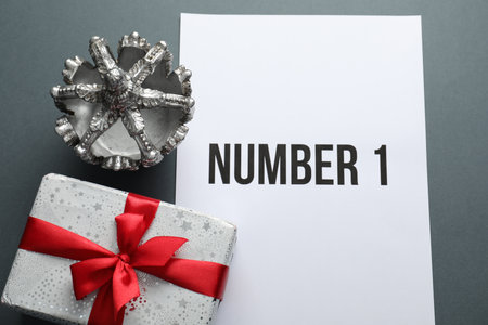 Sheet of paper with word Number 1, gift box and silver crown on grey table, flat layの写真素材