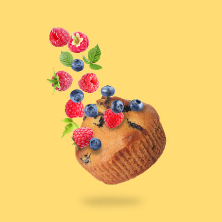 Delicious muffin and berries in air on golden backgroundの写真素材