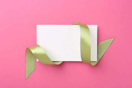 Blank card and olive ribbon on pink background, top viewの写真素材