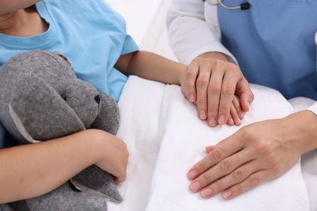 Doctor examining little girl on bed at hospital, closeupの写真素材