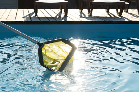 Cleaning swimming pool with skimmer net at luxury resortの写真素材