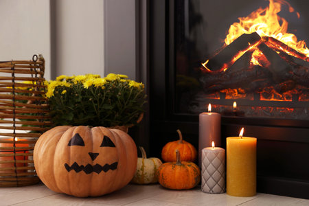 Pumpkins, burning candles and flowers near fireplace indoors. Halloween celebrationの写真素材