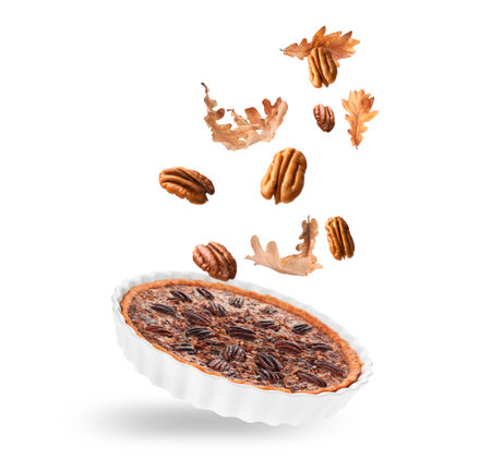 Autumn cake, pecan nuts and orange leaves in air on white background