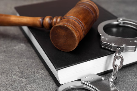 Book, judge's gavel and handcuffs on gray textured table, closeupの写真素材