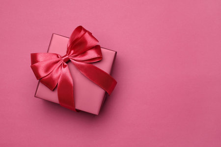 Gift box with bow on pink background, top view. Space for textの写真素材