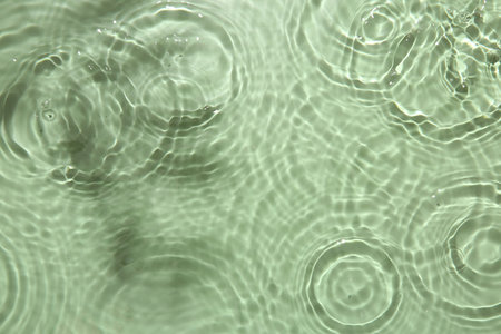 Rippled surface of clear water on light green background, top viewの写真素材