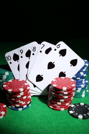 Poker chips and playing cards on green table
