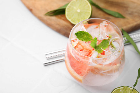 Refreshing water with grapefruit and mint in glass on white tiled table, closeup. pace for textの写真素材