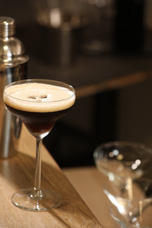 Glass with delicious espresso martini on wooden table in barの写真素材