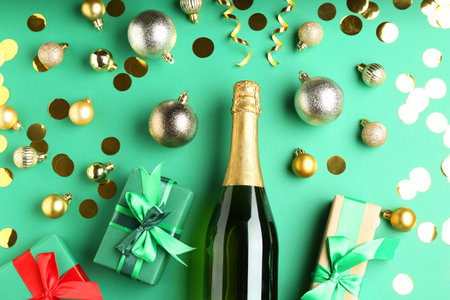 Flat lay composition with confetti and bottle of sparkling wine on green background. Christmas decorの写真素材