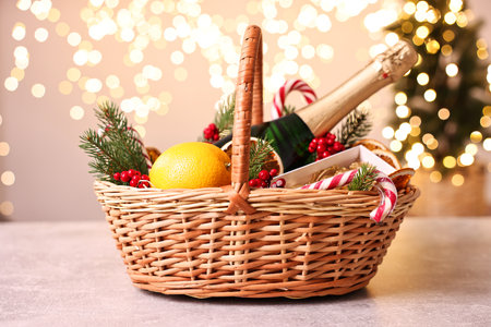 Wicker gift basket with sparkling wine and Christmas decor on light textured tableの写真素材