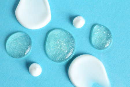 Smears of different cosmetic products on light blue background, flat layの写真素材