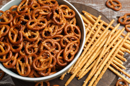 Delicious pretzel crackers and salty sticks on wooden table, above viewの写真素材