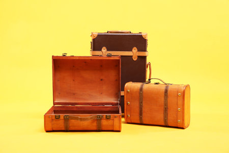 Three different brown suitcases on yellow backgroundの写真素材