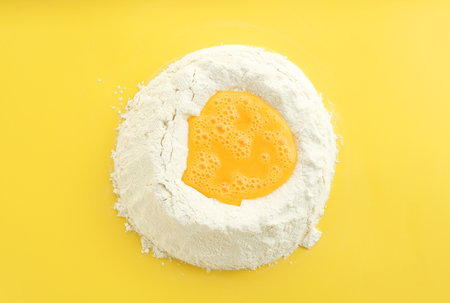 Cooking homemade pie. Flour with eggs on yellow background, top viewの写真素材