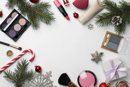 Frame of different decorative cosmetic products and Christmas decor on white background, flat lay. Space for textの写真素材