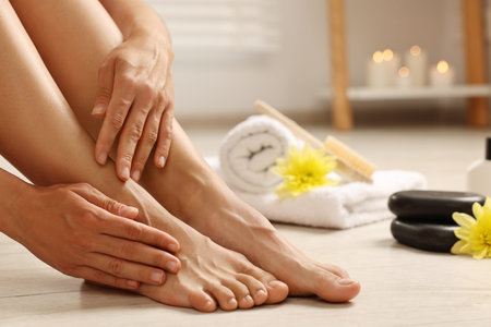 Woman touching her smooth feet on floor, closeup. Body careの写真素材