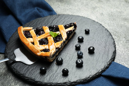 Piece of tasty homemade pie with blueberries and server on gray tableの写真素材