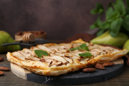 Delicious puff pastry tart with pears, almond and mint on wooden table, closeupの写真素材