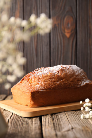 Tasty sponge cake with powdered sugar on wooden tableの写真素材