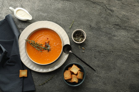 Delicious pumpkin soup with spices served on gray textured table, flat lay. Space for textの写真素材