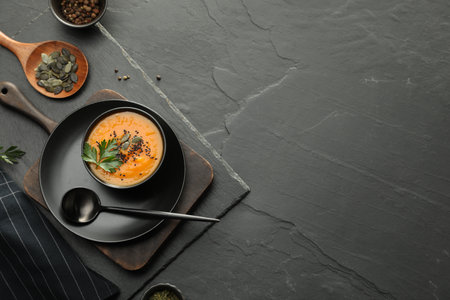 Delicious pumpkin soup with spices served on dark textured table, flat lay. Space for textの写真素材